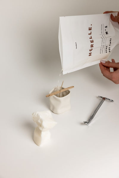 Main versant la cire fondue de la recharge dans le contenant en céramique
