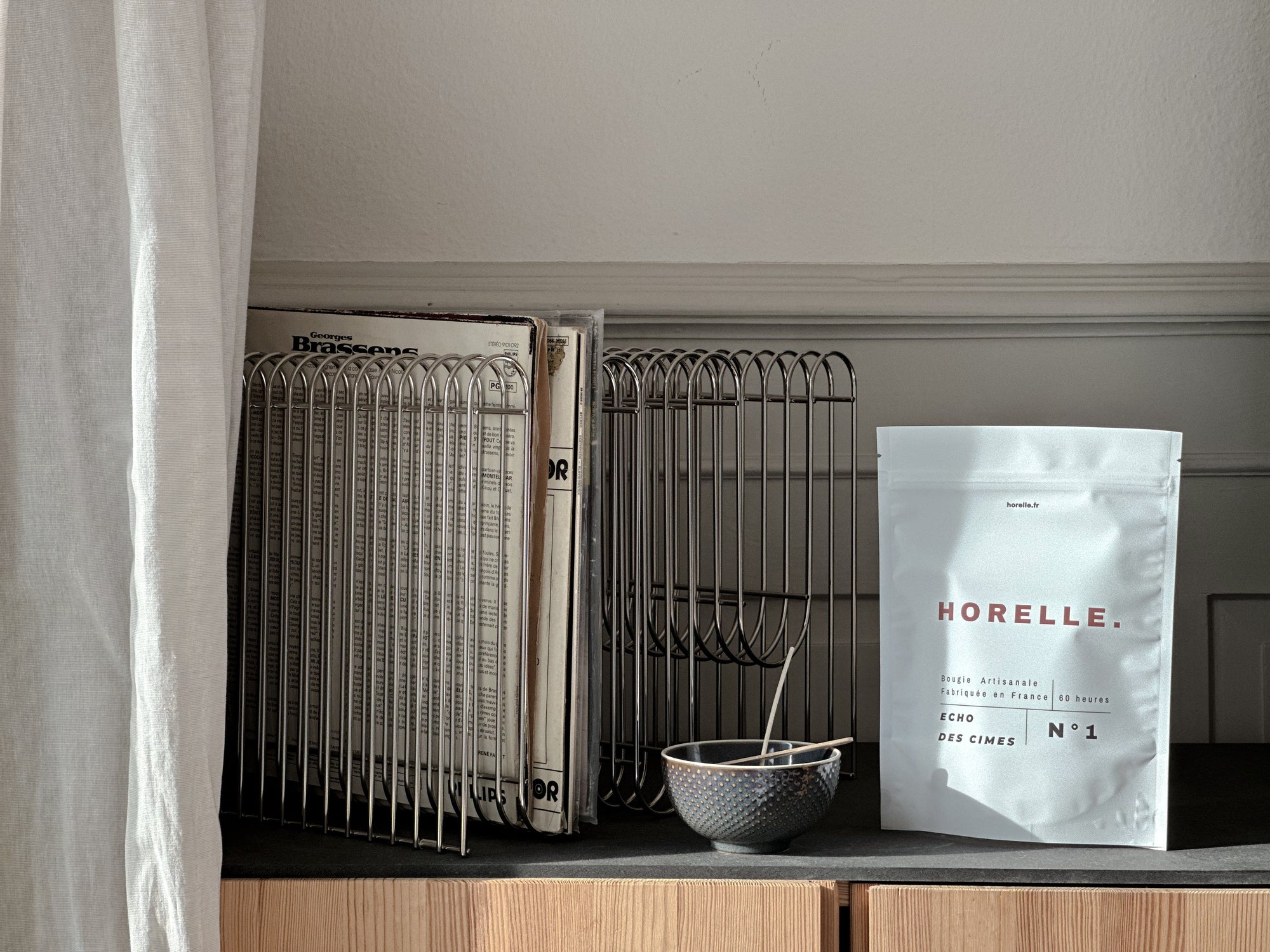 Recharge Horelle posée sur une enfilade en bois, à côté d'une collection de vinyles