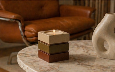 Le contenant signature Horelle allume sur une table basse en marbre, fauteuil en cuir